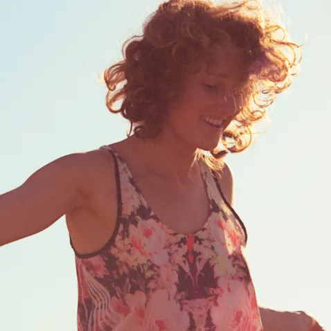Woman outdoors with arms open, dancing in golden light